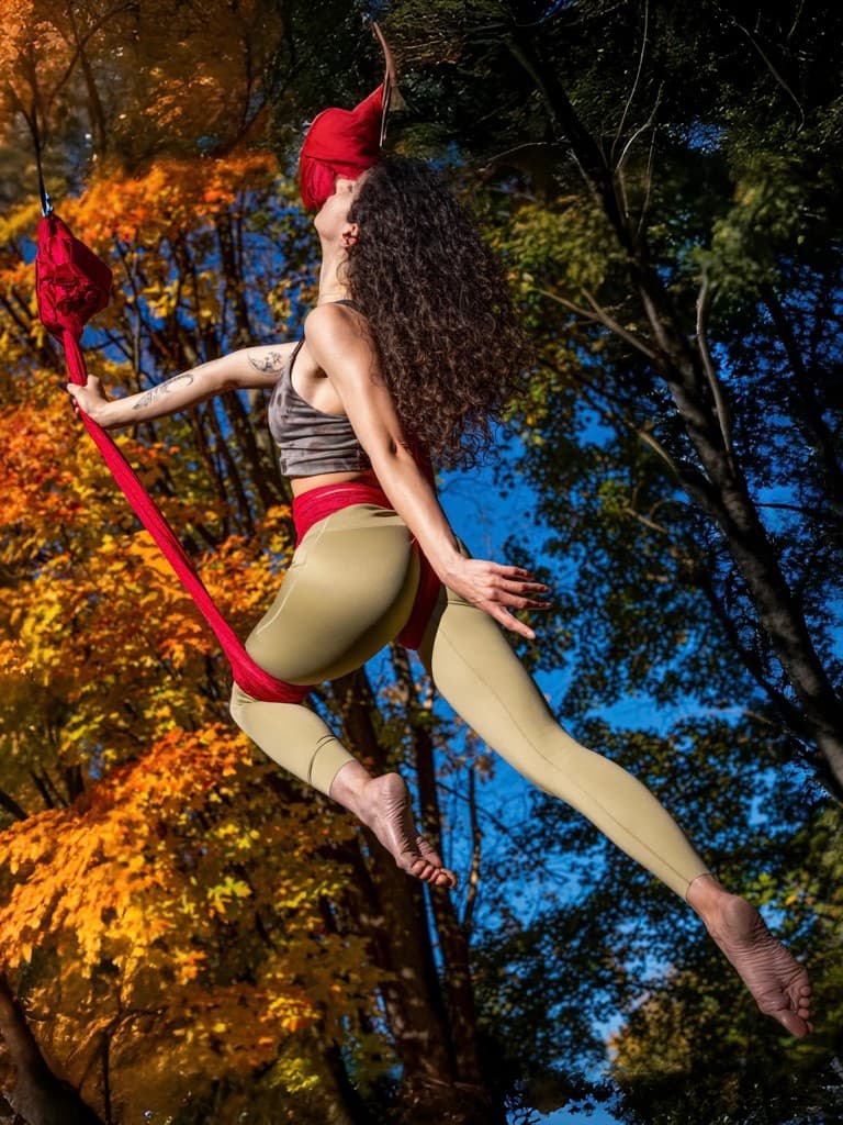 Linda Chavoshi performing aerial silks outdoors among autumn trees