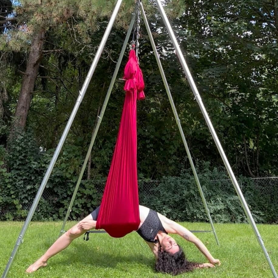 Linda in a supported yin aerial backbend in a red hammock outdoors