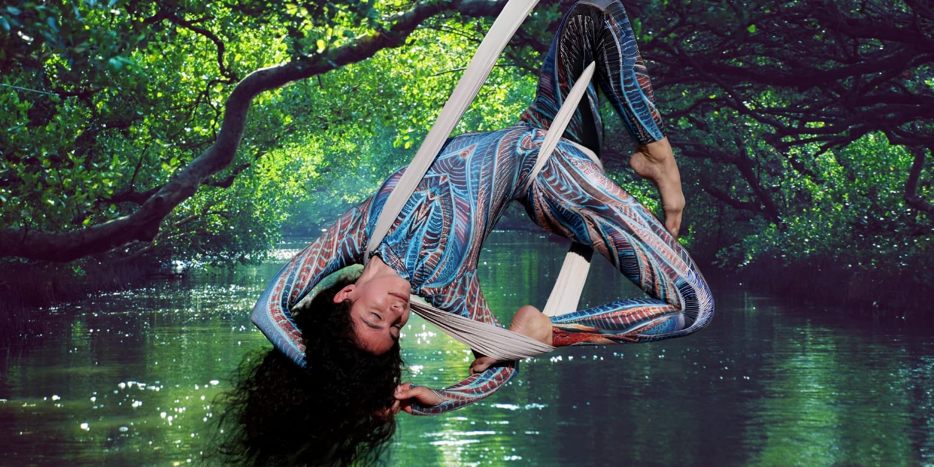 Linda suspended in aerial silks above a forest pond