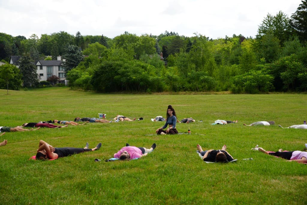 Linda with students in an outdoor yoga class on the grass